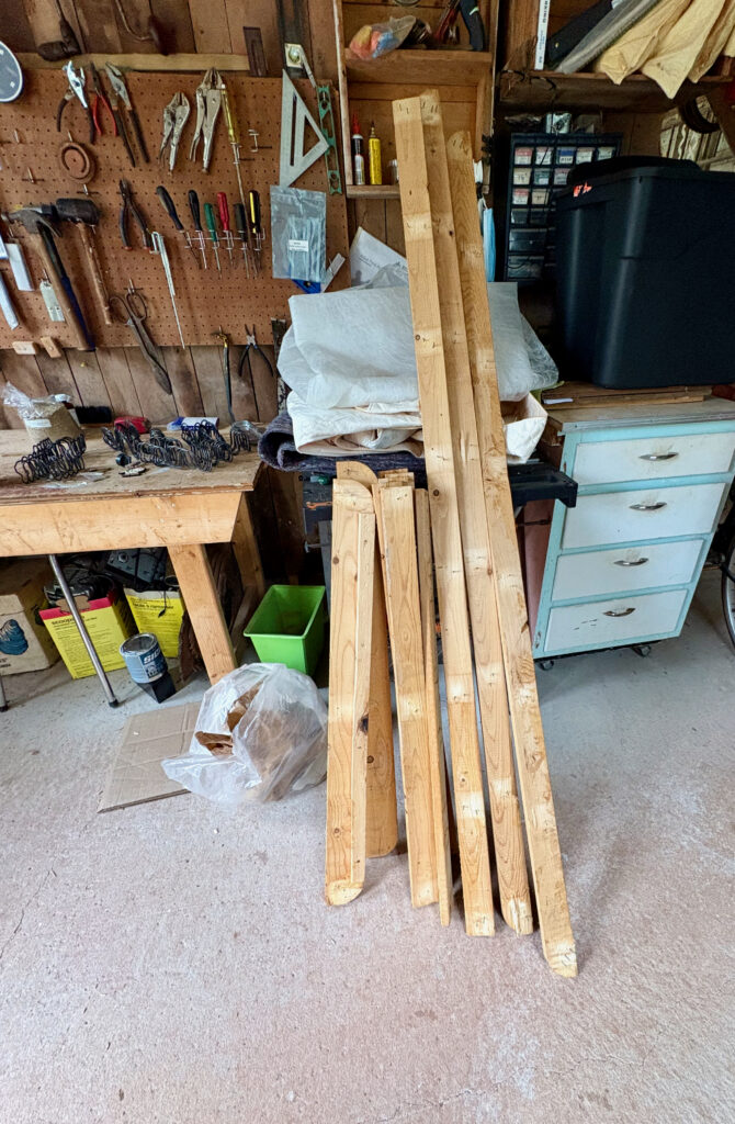 Lumber leaning against a workbench in a messy workshop.