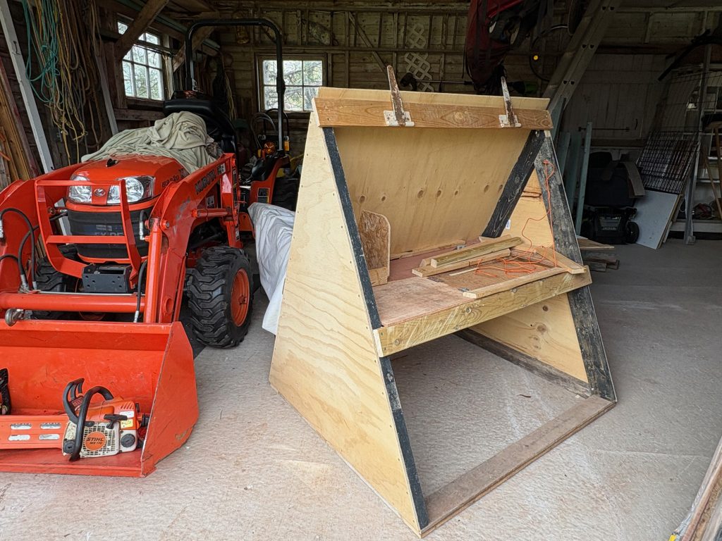 A portable chicken coop with an orange Kubota tractor on the left.